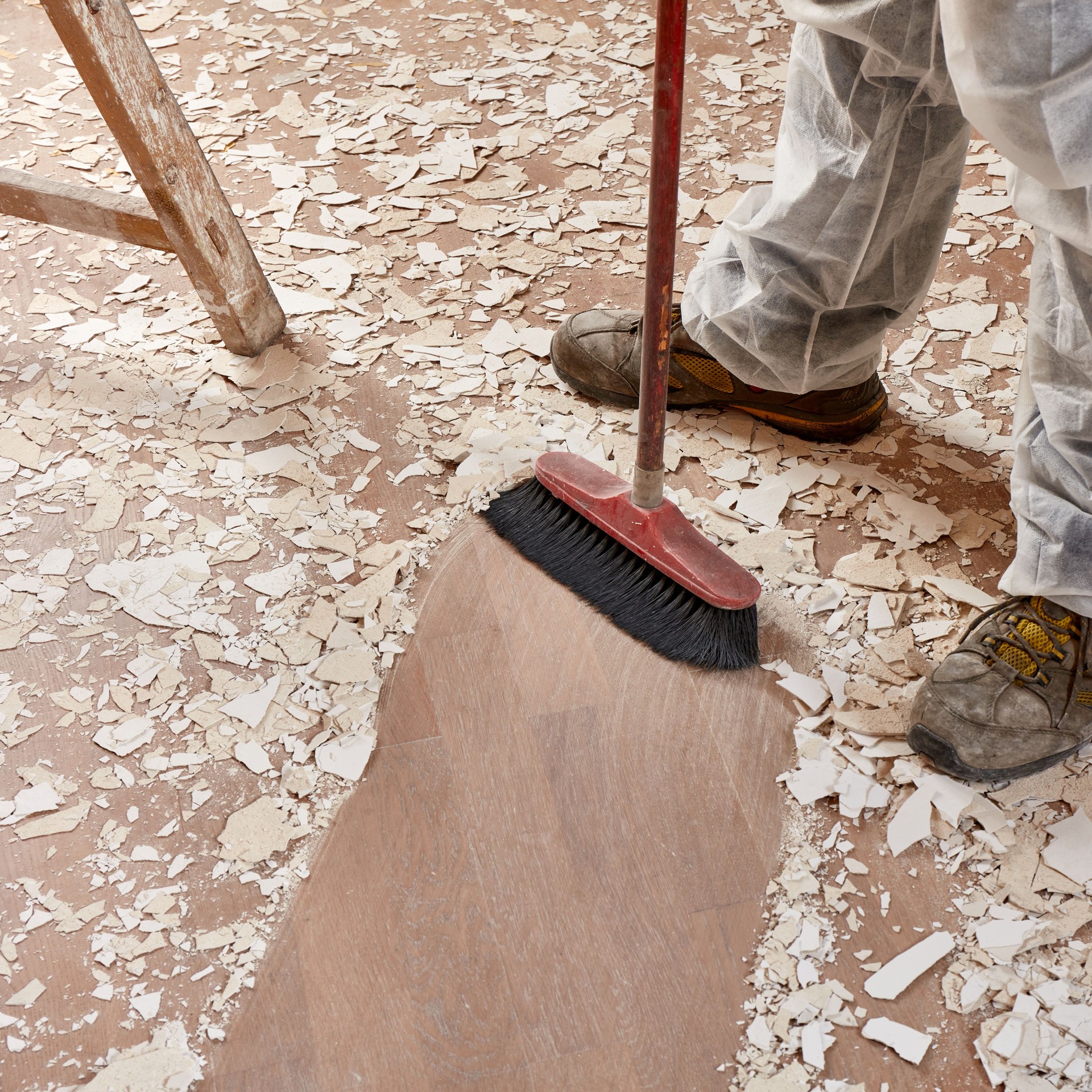 Builder sweeping the floor after renovation